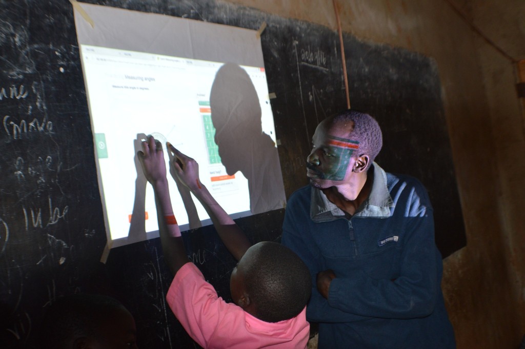 Mr Alex Anyova, a class five maths teacher looks on as one of his pupils measures angles using educational materials projected from RACHEl. 